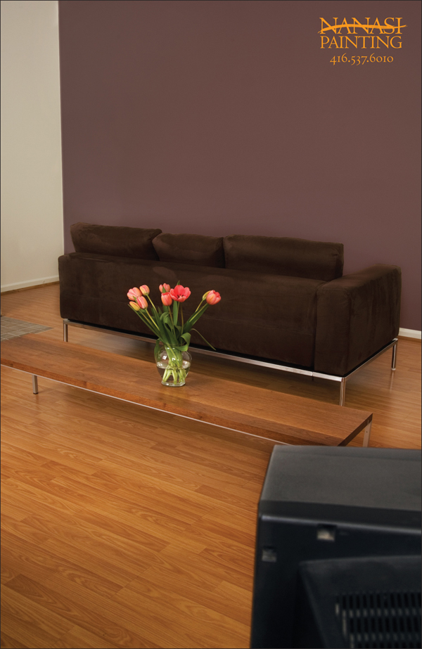 A couch faces a beautifully painted wall instead of the television which is on the opposite side of the room.