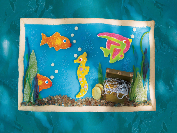 An aquarium cookie complete with angel fish, seahorse, tropical fish and a treasure chest, all made of cookies within a cookie and colourful icing.
